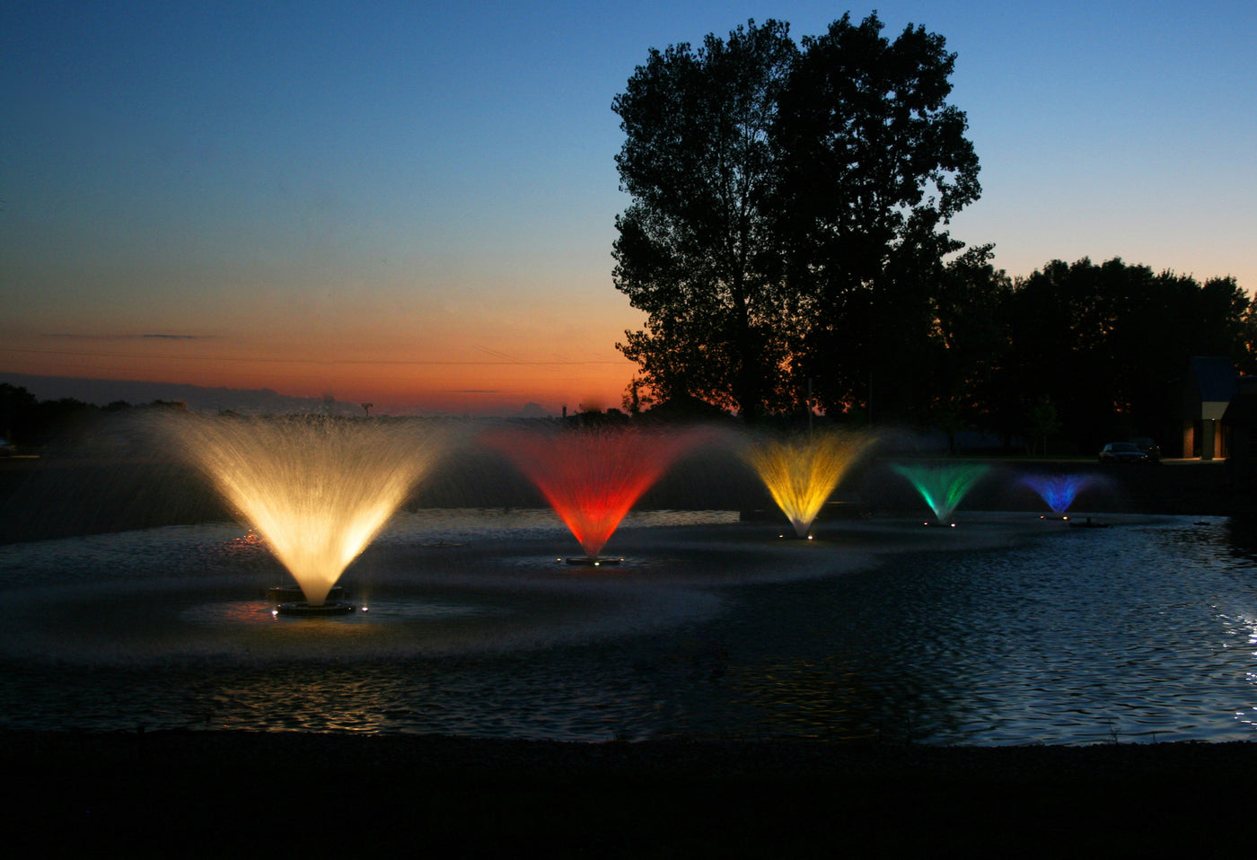 Different sized Kasco Aerating Fountains operating in a pond with different colored lights