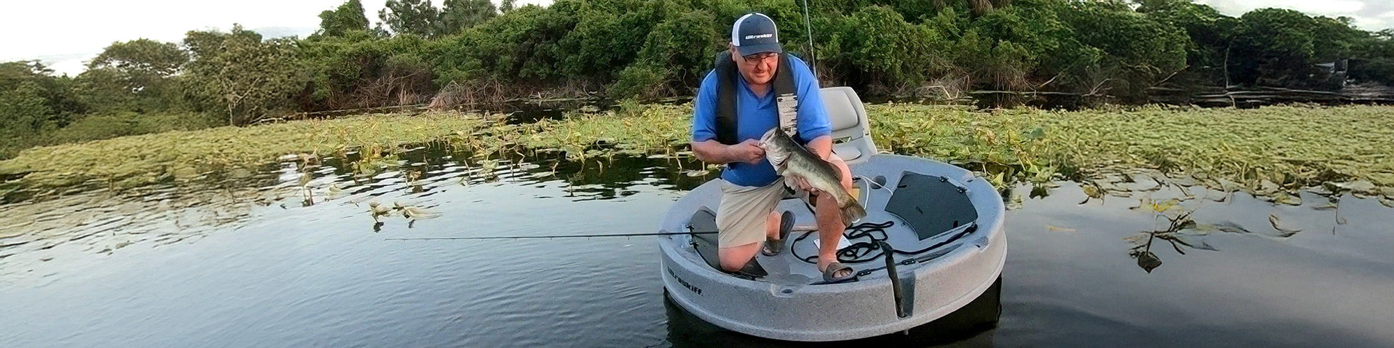 Man on Ultraskiff round boat landing a bass