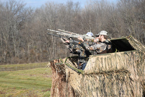 Hunters aiming guns out of blind