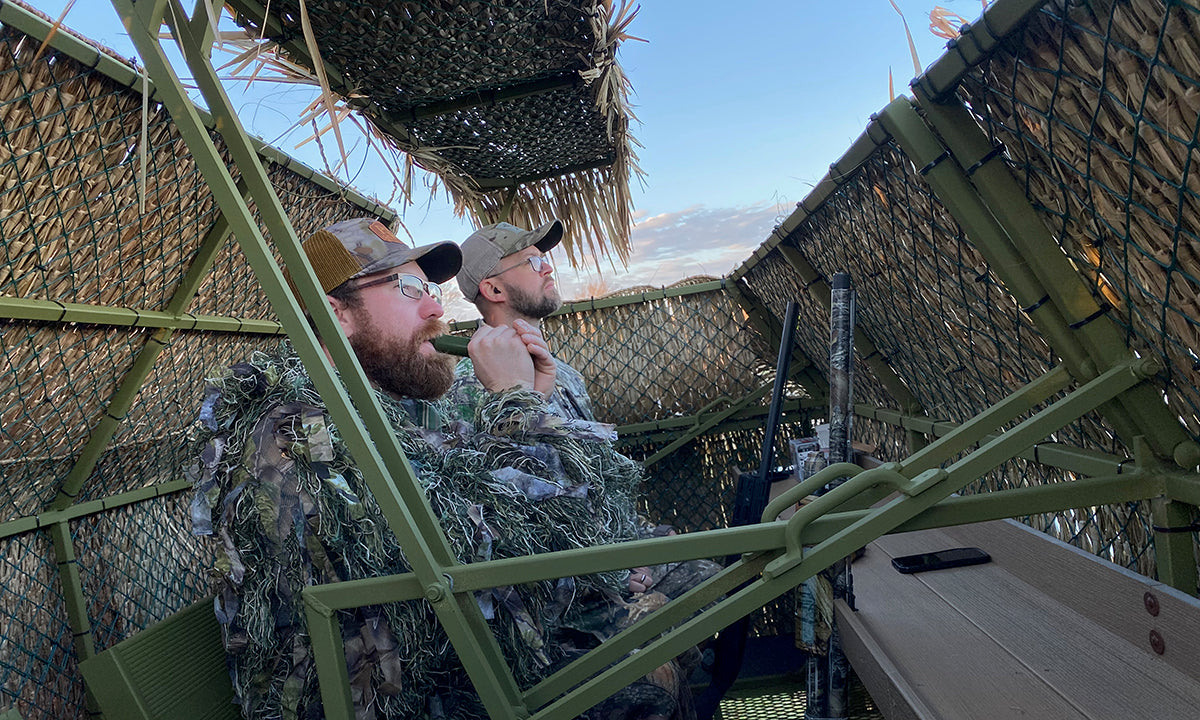 hunters using duck call in blind