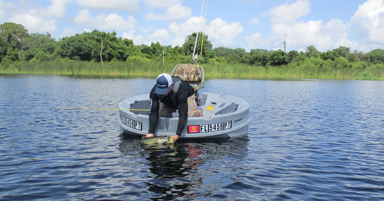 person leaning over ultraskiff with big fish